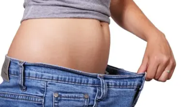 Žena drží rozepnuté džíny kvůli hubnutí po úpravě trávení.