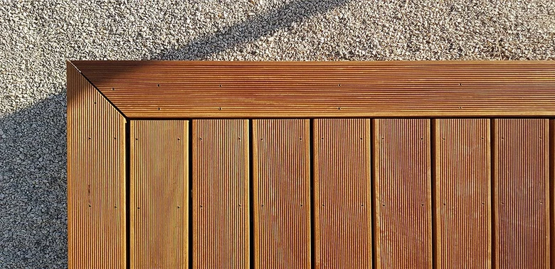 Detail dřevěné terasy s rohovým spojem na štěrku.