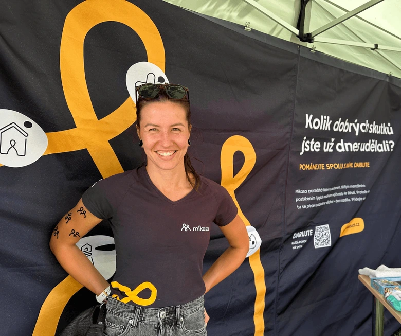 Žena stojí před plakátem s žlutou stužkou pro autistickou komunitu.