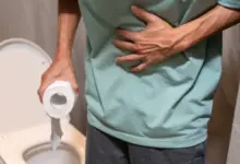 Muž drží toaletní papír a stiská si břicho kvůli průjmu.