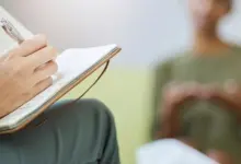 Psycholog zapisuje poznámky během sezení s klientem.