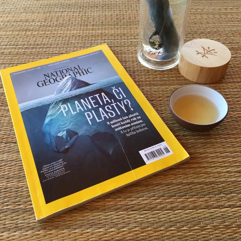 Časopis National Geographic o plastech v oceánu s čajem na podložce.