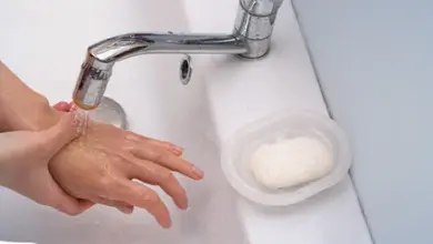 Umývání rukou pod tekoucím vodovodním kohoutkem s mýdlem.