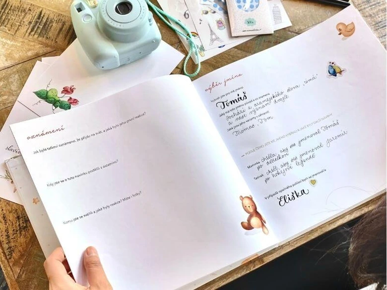 Otevřená kniha s českými jmény pro děti vedle fotoaparátu