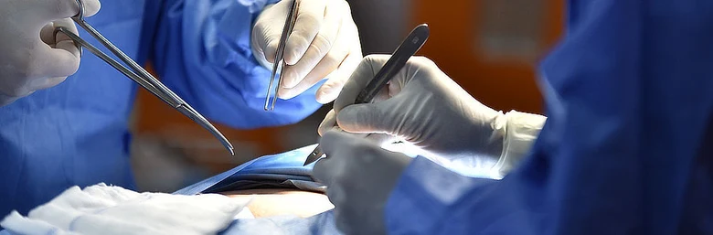 Chirurgové operují pacienta v nemocničním prostředí s nástroji.