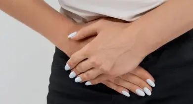 Žena drží bolavé stydké pysky rukama.