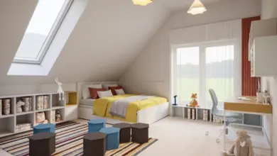 Moderní obytné podkroví s postelí, pracovním stolem a velkým oknem.