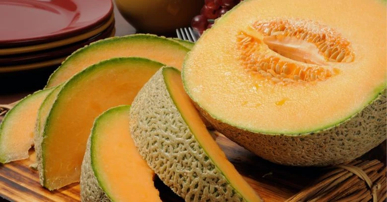 Čerstvé plátky melounu cantaloup na dřevěném talíři.