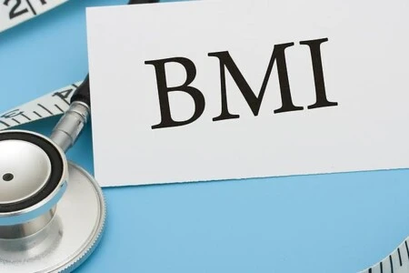 Bílá karta s nápisem BMI vedle posilovače na modrém pozadí.
