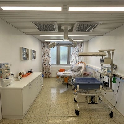 Modern porodní místnost s lůžkem a lékařským vybavením.