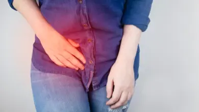 Žena drží dolní břicho s červeným zvýrazněním bolesti.