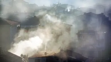 Hustý smog zakrývá střechy domů v městské zástavbě.