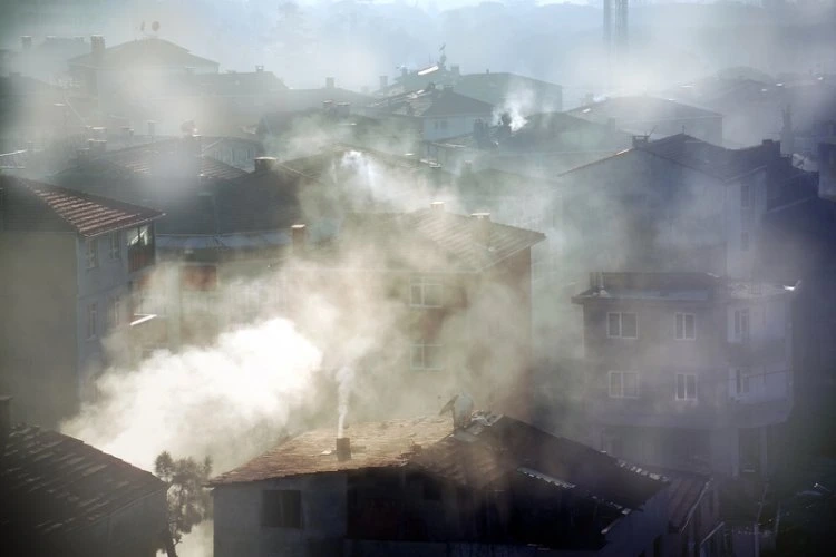 Hustý smog zakrývá střechy domů v městské zástavbě.