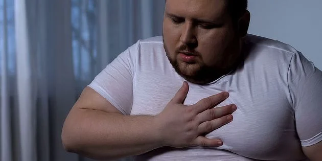 Muž drží ruku na hrudi při bolestech srdce.