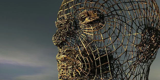 Sculptura lidské hlavy z drátů na pozadí oblohy.