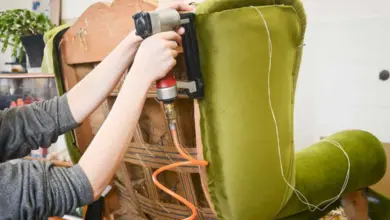 Osoba přitahuje zelený potah k židli pomocí pneumatického nůžky.